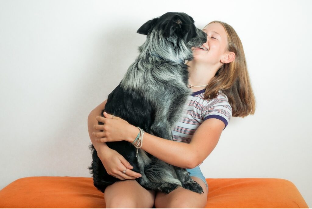 Dog on girls lap licking her face